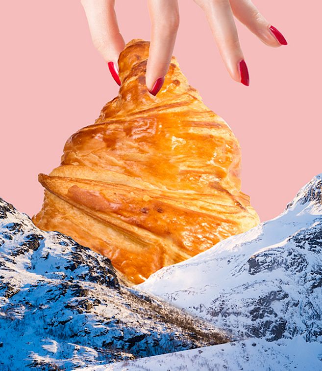Hand mit roten Nägeln hält ein Croissant wie einen Berggipfel über schneebedeckten Bergen, rosa Hintergrund.