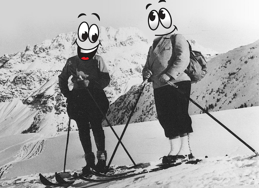 Deux skieurs avec des visages de dessin animé posent dans un paysage montagneux enneigé.