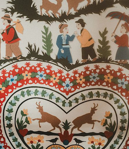 People and animals in traditional paper-cut design with floral heart motif