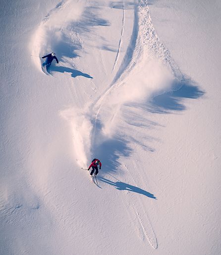 Deux personnes skient sur une piste de montagne enneigée dans la poudreuse fraîche.