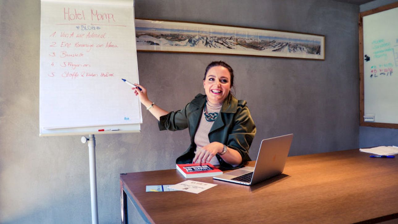 Femme présentant joyeusement des informations sur un tableau à feuilles mobiles à côté d'un ordinateur portable.