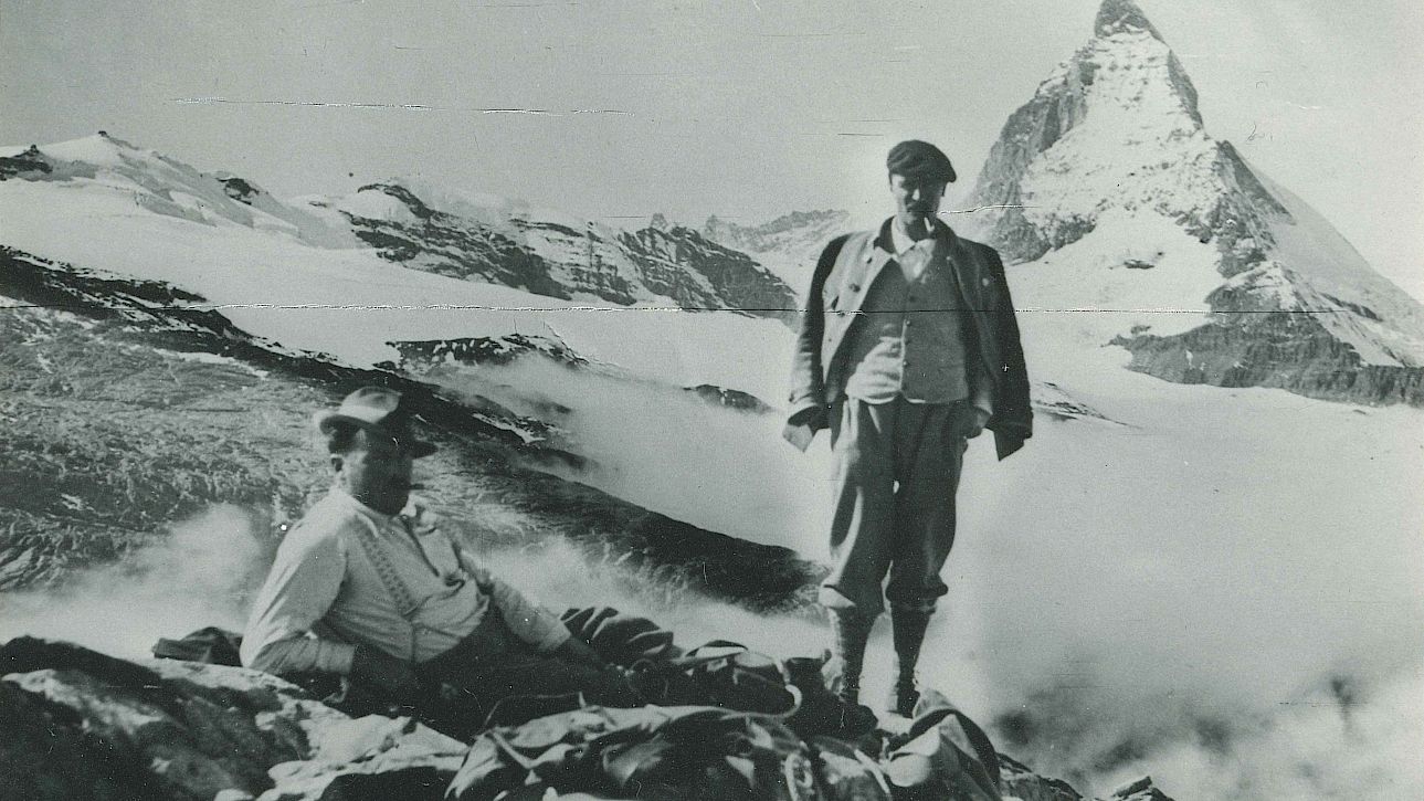 Deux alpinistes se reposent devant le Cervin, entouré de sommets enneigés.
