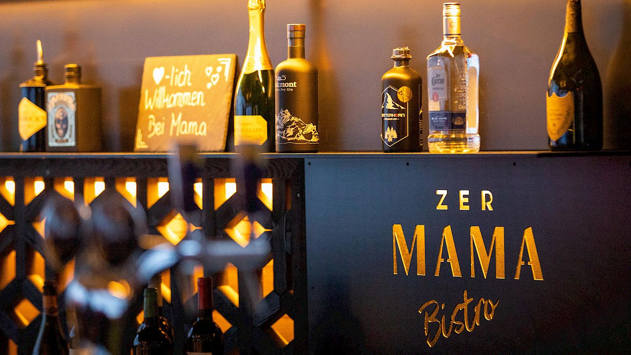 Bottles and a welcome sign on a shelf at Zer Mama Bistro. Cozy bistro atmosphere.