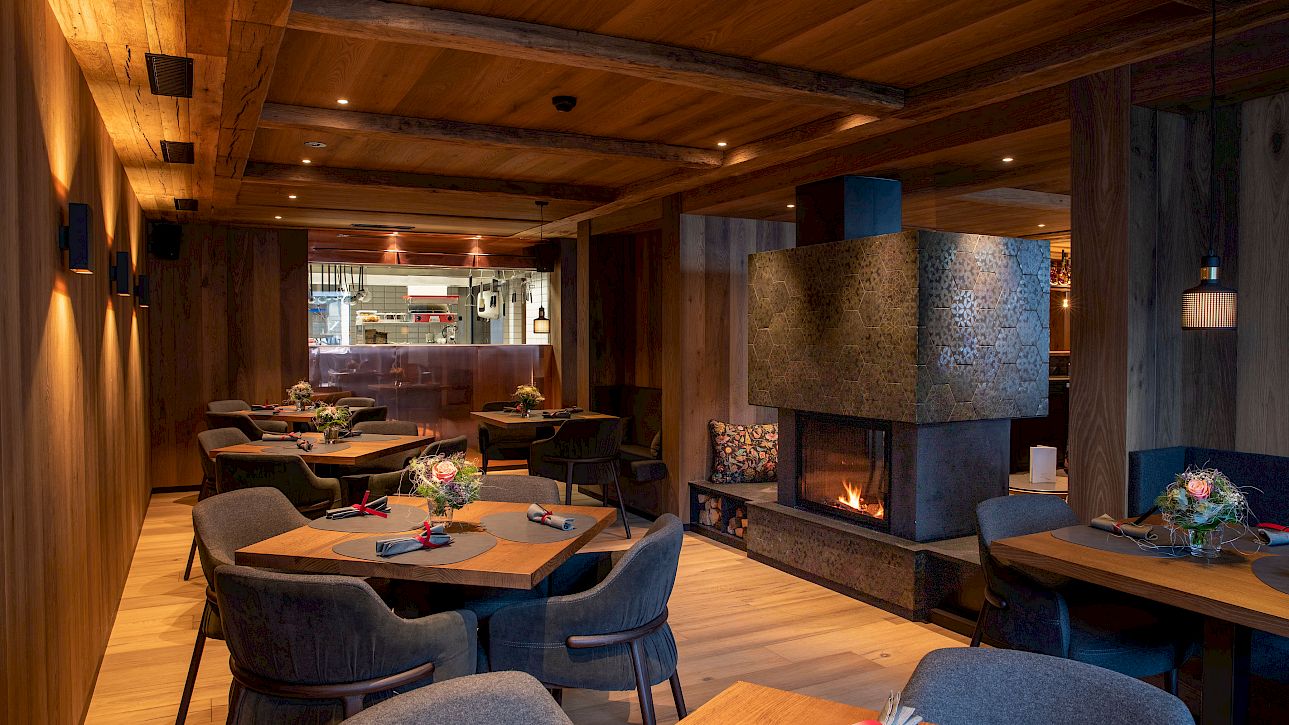 Cozy restaurant with wooden walls, fireplace, elegant decor, and modern set tables.