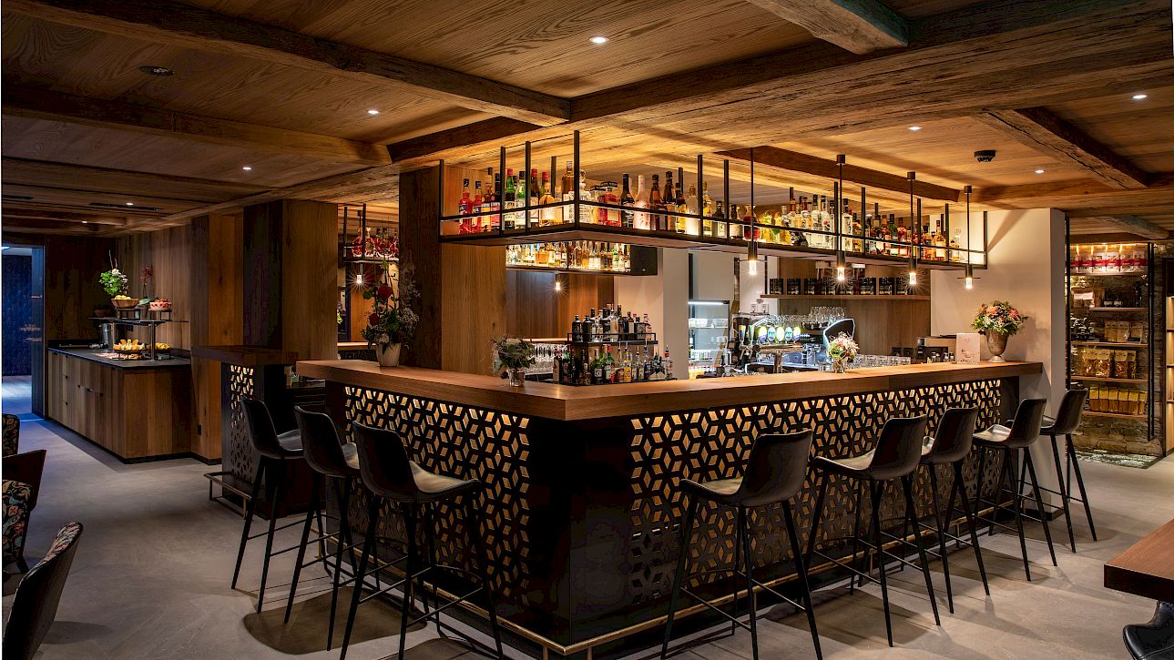 Elegant bar with wooden decor, high ceiling, and well-stocked bottle shelves in the background.
