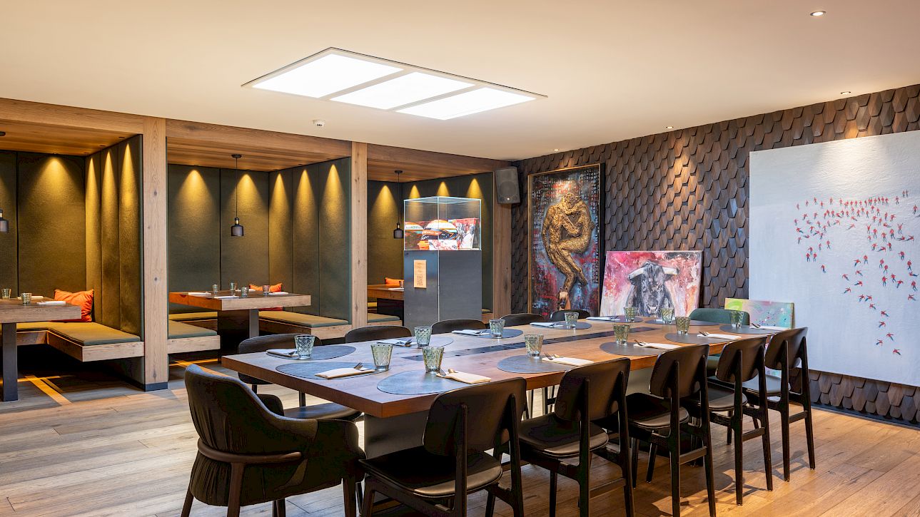 Elegant restaurant interior with long table, unique artworks, and cozy seating nooks.