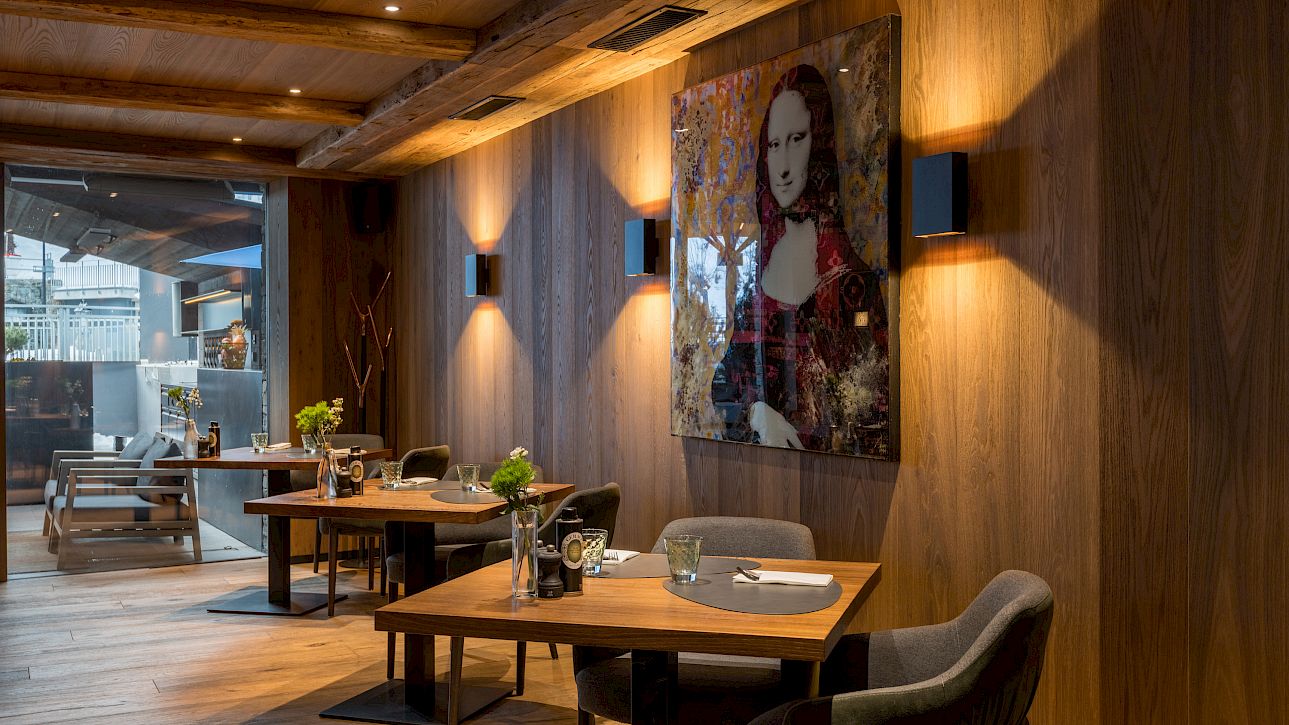 Modern restaurant interior with wooden walls, set tables, and a pop art-style Mona Lisa painting.