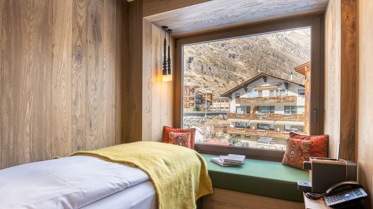 Cozy room with wood decor and window seat, offering view of snowy mountain chalets.
