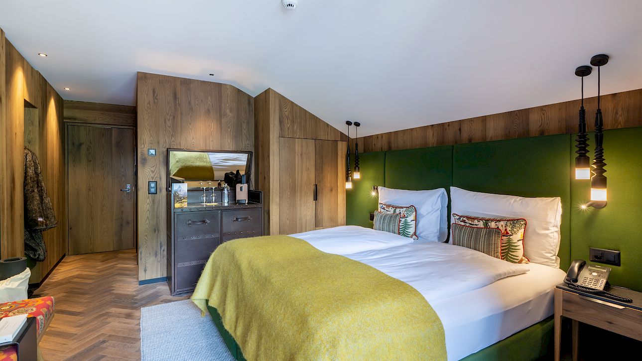 Gemütliches Hotelzimmer mit einem großen Bett, Holzwänden und modernen Lampen. Warmes und einladendes Ambiente.