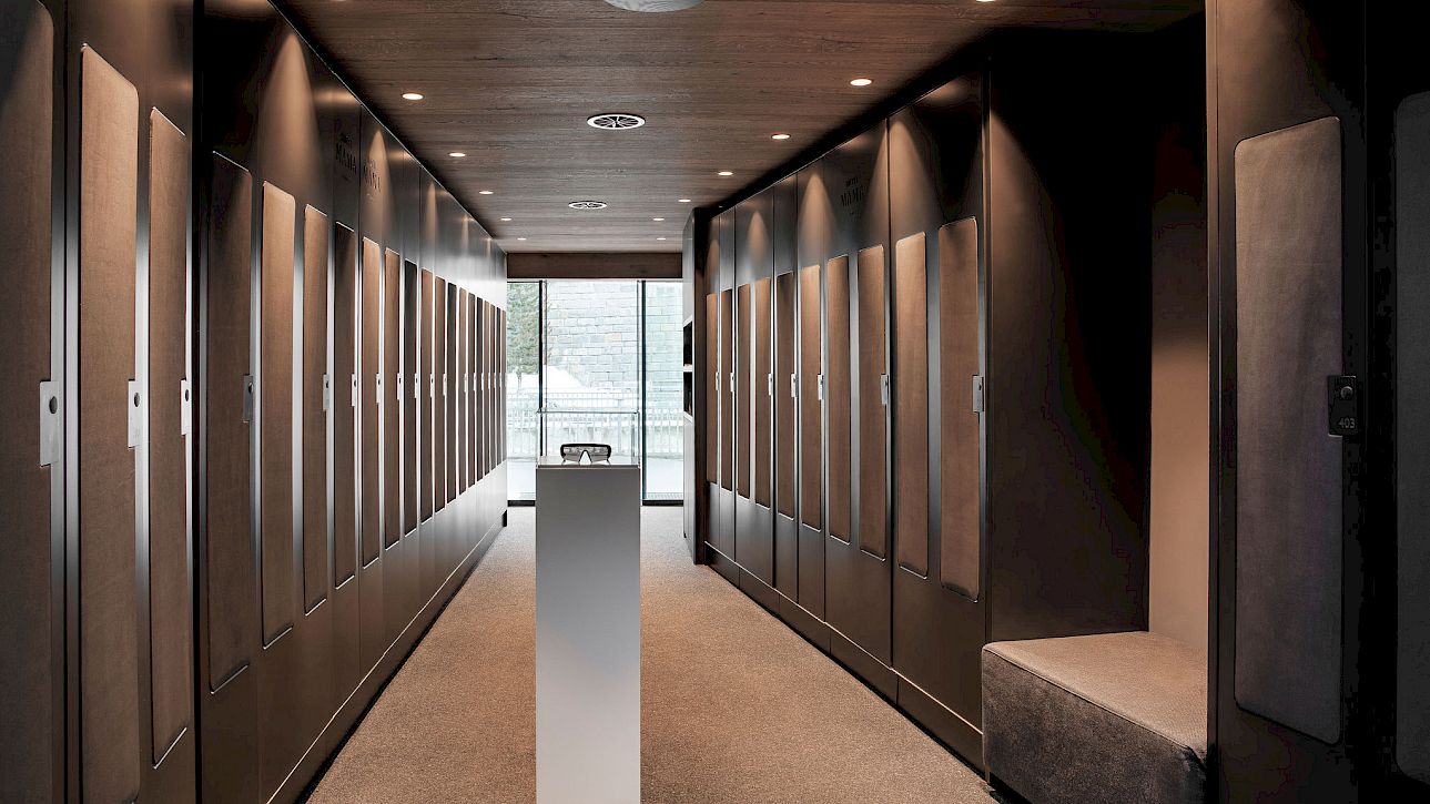 Un vestiaire moderne et élégant avec un long couloir, des casiers et un piédestal au centre.