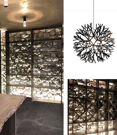 Salle moderne avec table en bois et lumière de plafond en branches, mur en pierre décoratif en arrière-plan.