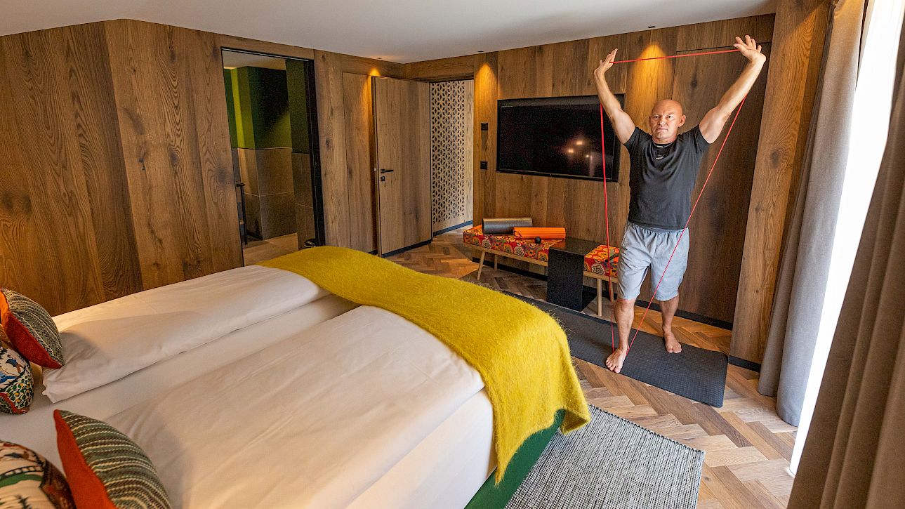 Un homme fait des exercices d'étirement avec un élastique de fitness dans une chambre d'hôtel moderne et confortable.