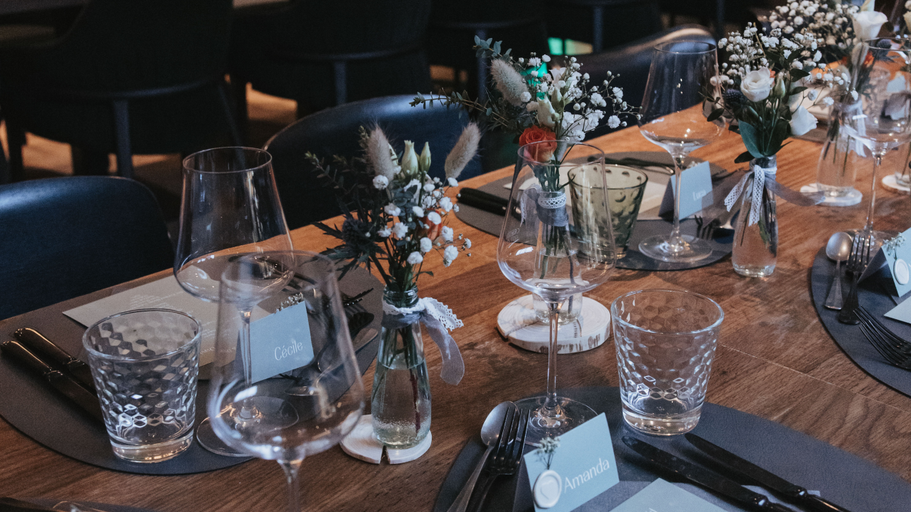 Élégante décoration de table avec vases, verrerie et cartes de place dans un cadre de restaurant chic.