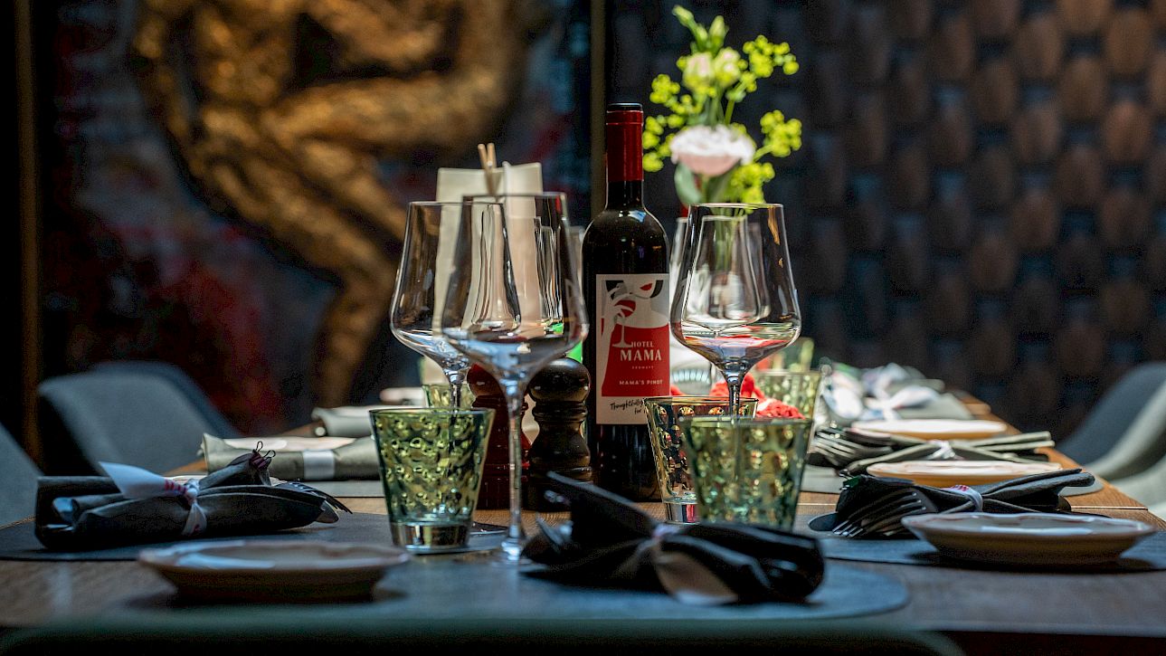 Table élégante dans un restaurant avec verres à vin, bouteille de vin et décor artistique.