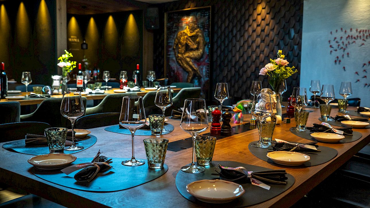 Intérieur de restaurant élégant avec table dressée, verres à vin et éclairage chaleureux.