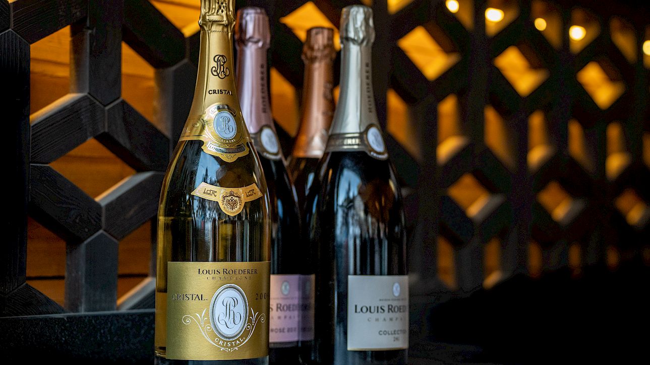 Champagne bottles on a table, with a decorative wooden lattice background and warm lighting.