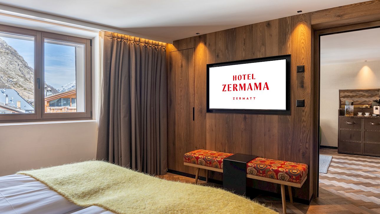 Gemütliches Hotelzimmer mit Holzverkleidung und Blick nach draußen; Banner: Hotel ZERMAMA.