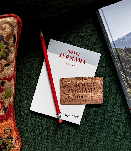 Bunte Kissen, Notizblock und Buch über Zermatt auf grünem Hintergrund.