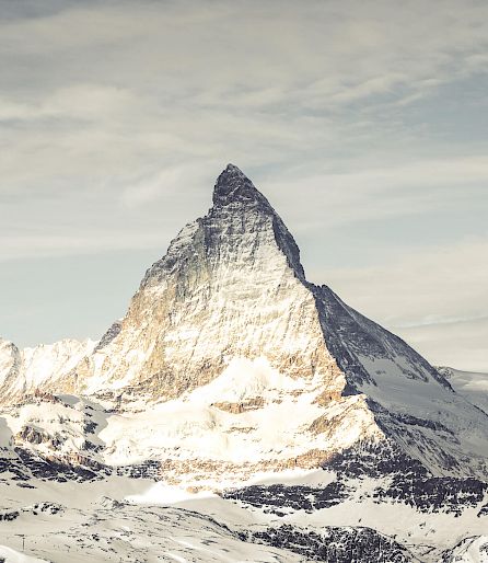 Verschneite Berglandschaft mit dem Matterhorn unter blauem Himmel.