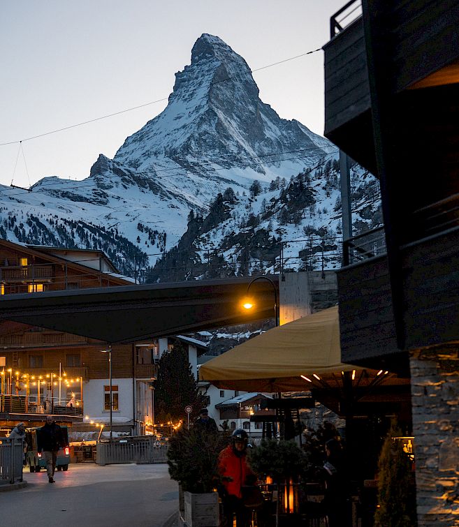 Street scene in an Alpine town at dusk, with the Matterhorn in the background.