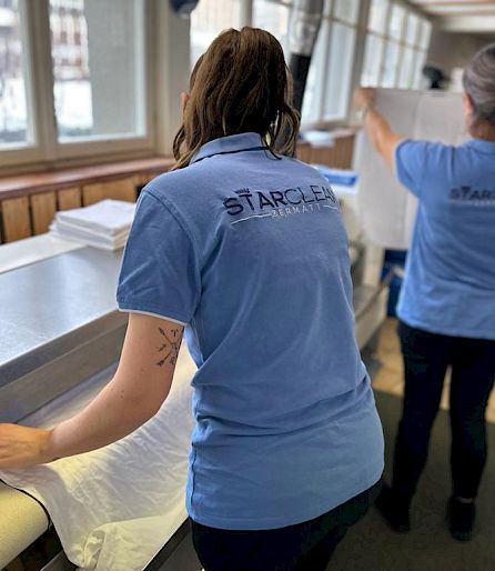 Two people in blue "Starclean" shirts working in a laundry room.