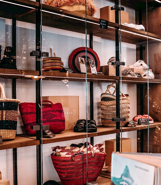 Shelves displaying various bags and accessories in a store, including baskets and hats.