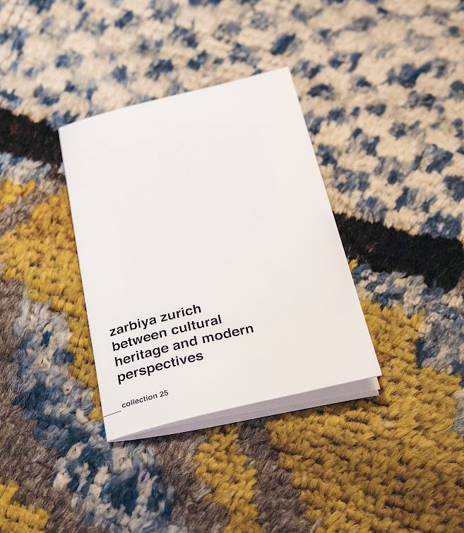A book titled "zariya zurich" on a patterned carpet.